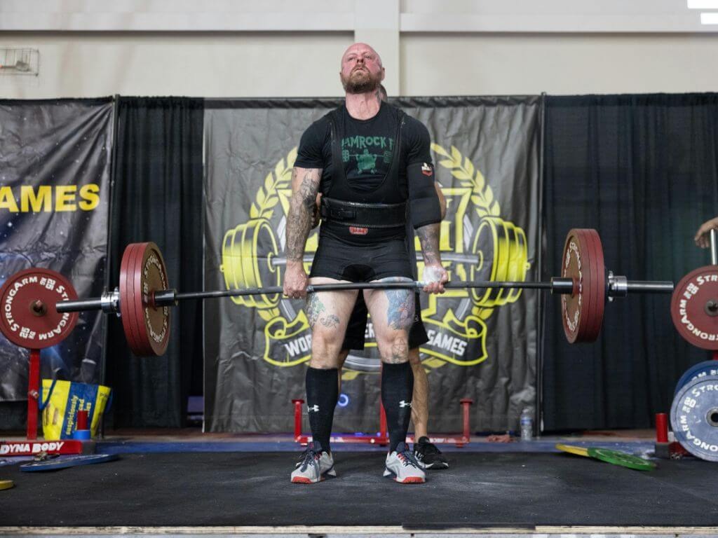 Tactical athlete executing a heavy deadlift to full lockout with controlled barbell mechanics